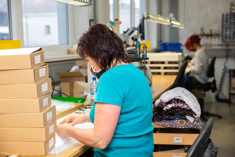 Mitarbeiterin in der Produktion beim Verpacken von Brillenfassungen